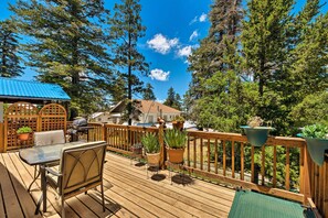 A wooden deck with a table and chairs, surrounded by potted plants and a view of a house and trees. - Cabin w/ Deck 3 Mi to Ski Cloudcroft & Hiking (Cloudcroft)