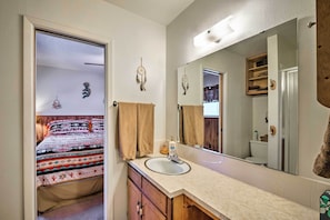 A bathroom with a sink, mirror, and wooden cabinets. - Cabin w/ Deck 3 Mi to Ski Cloudcroft & Hiking (Cloudcroft)