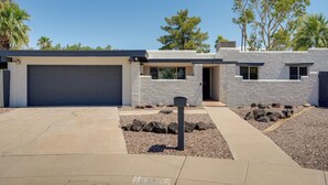 A modern house with a garage, a driveway, and a landscaped garden with rocks and trees. - Phoenix Home w/ Pool, Near Golf, Hiking & More! (Phoenix)