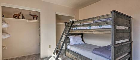 A bunk bed with a ladder, a shelf with animal figurines, and a small blue bucket.