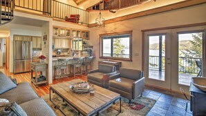A spacious living area with a high ceiling, a kitchen, and a balcony with a view. - Swim, Boat & Explore! South Lake Coeur D'alene Gem (Worley)
