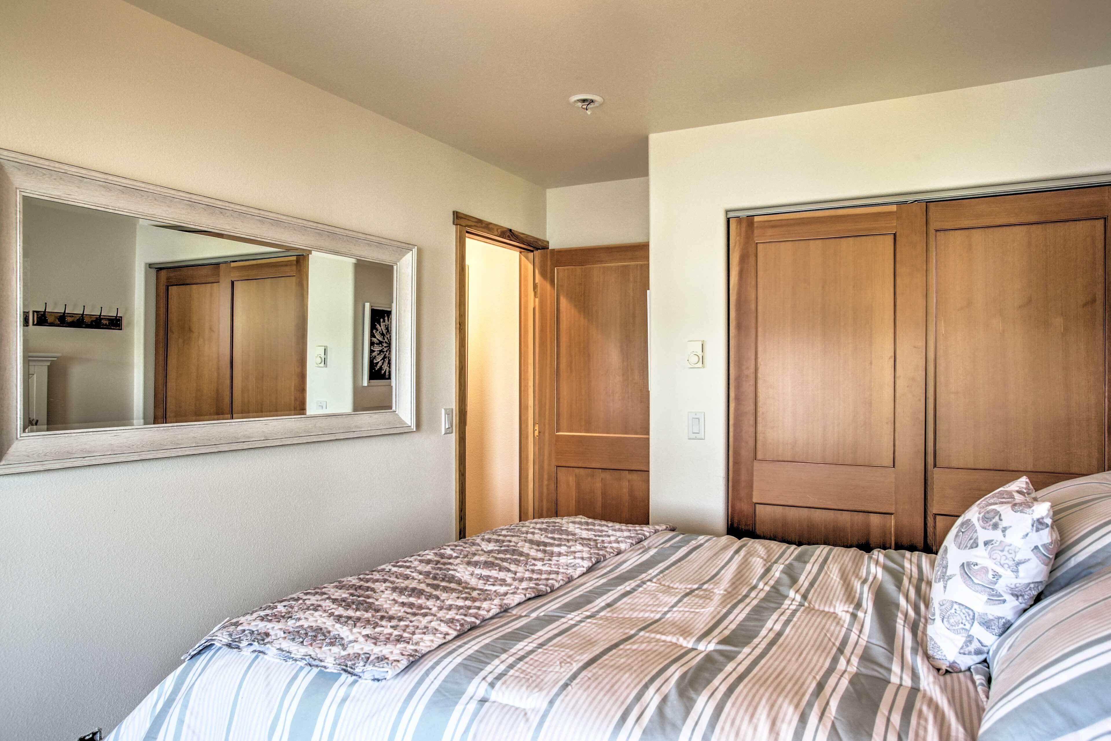 A bedroom with a bed, a large mirror, and wooden wardrobes.