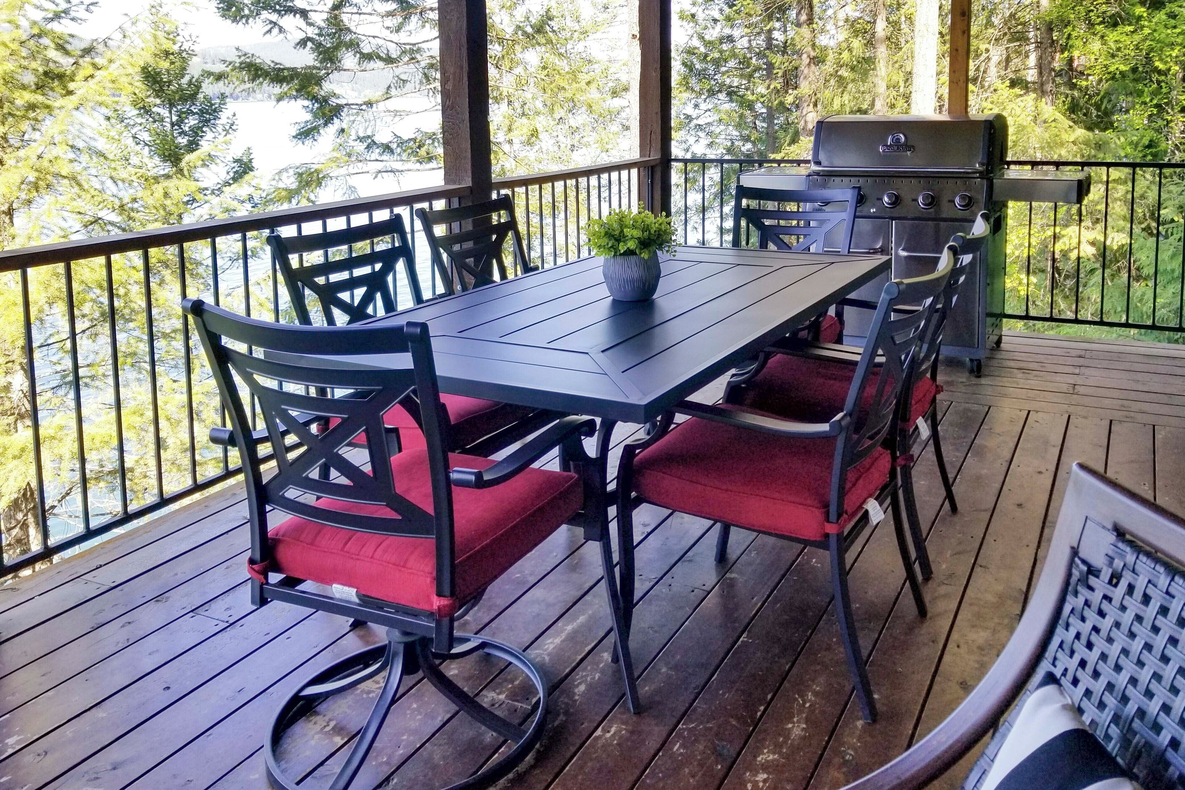 Eine überdachte Terrasse im Freien mit Tisch, Stühlen, einem Grill und einem Blumentopf.