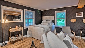 A bedroom with a bed, two windows, a chair, a small table, and a floor lamp. - Country-chic Waxhaw Studio w/ Pool Access! (Waxhaw)