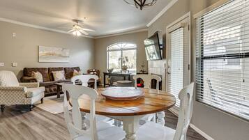 A dining area with a round wooden table, white chairs, and a ceiling fan.