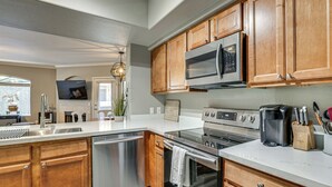 A modern kitchen with wooden cabinets, stainless steel appliances, and a marble countertop. - Close to Golfing & Shopping: Condo in Scottsdale! (Scottsdale)