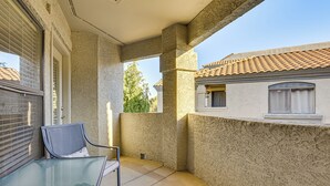 A balcony with a glass table and chair, a view of neighboring buildings, and a clear sky. - Close to Golfing & Shopping: Condo in Scottsdale! (Scottsdale)