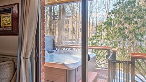 A hot tub on a wooden deck with a glass door leading to a room. - Pet-friendly Gilford Home by Gunstock Ski Mountain (Gilford)