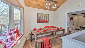 A dining area with a wooden table set for six, a bench, and a window seat with cushions. - Pet-friendly Gilford Home by Gunstock Ski Mountain (Gilford)