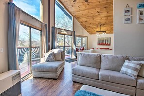 A spacious living room with a large window, a wooden ceiling, and a cozy seating area. - Pet-friendly Gilford Home by Gunstock Ski Mountain (Gilford)