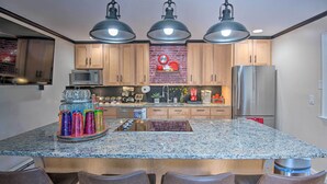 A kitchen with granite countertops, wooden cabinets, a stainless steel refrigerator, and pendant lighting. - Pet-friendly Gilford Home by Gunstock Ski Mountain (Gilford)