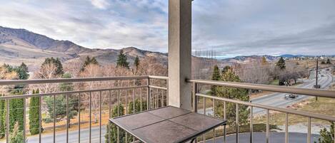 A balcony with a table and a view of a road and mountains.