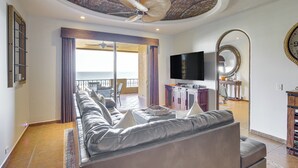 A spacious living room with a leather sofa, a ceiling fan, a flat-screen TV, and a balcony with a view. - Beachfront Rocky Point Villa w/ Ocean Views! (Puerto Peñasco)