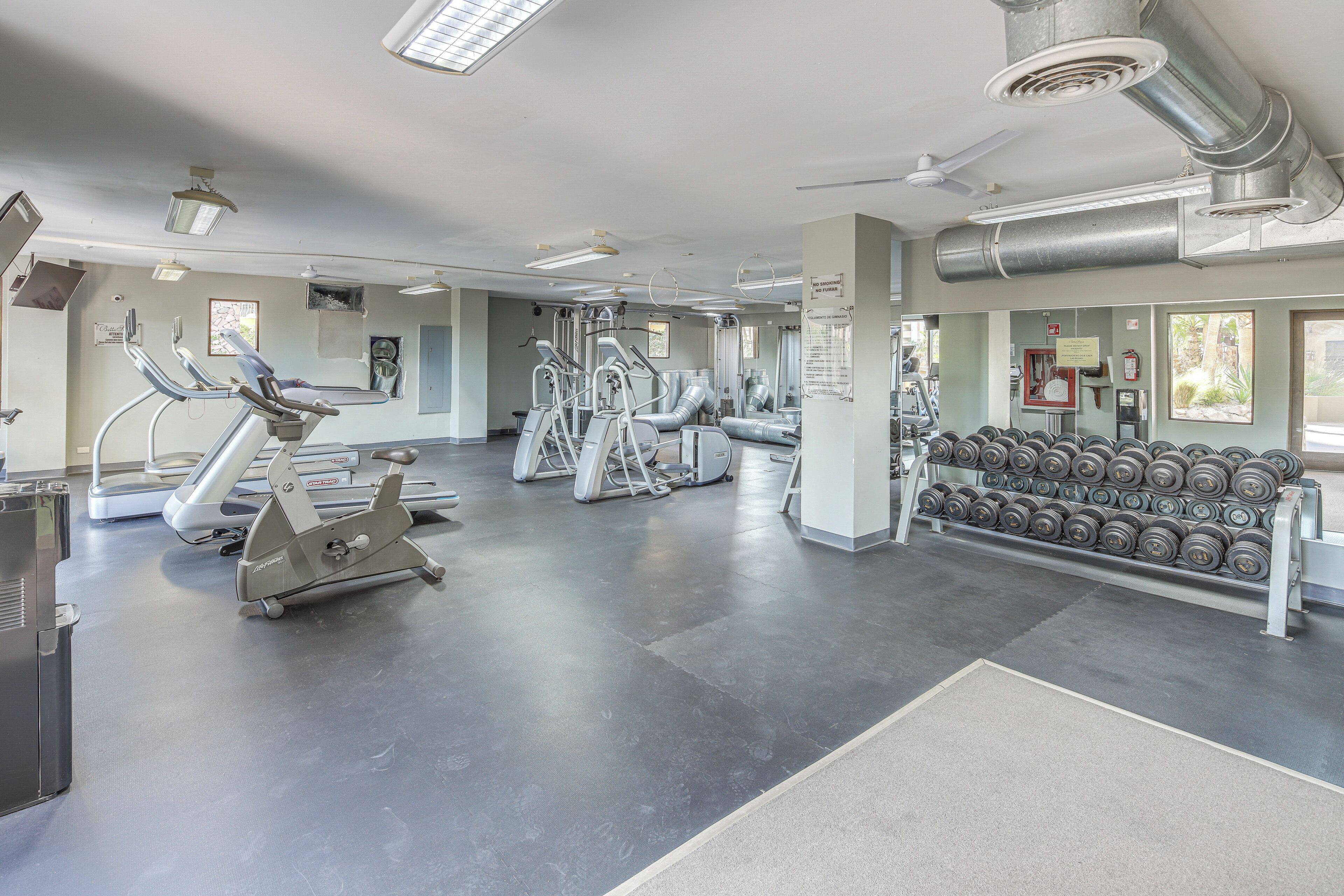Ein Fitnessraum mit Cardiogeräten, Krafttrainingsgeräten und Kurzhanteln.