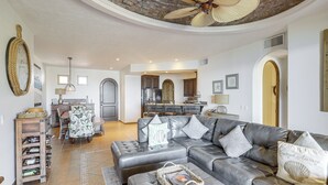 A spacious living room with a grey sectional sofa, a coffee table, and a dining area with a chandelier. - Beachfront Rocky Point Villa w/ Ocean Views! (Puerto Peñasco)
