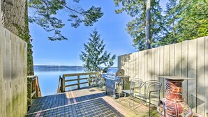 A wooden deck with a grill and chairs overlooking a lake. - Cozy Beachouse: View & Deck, Steps From Skagit Bay (La Conner)