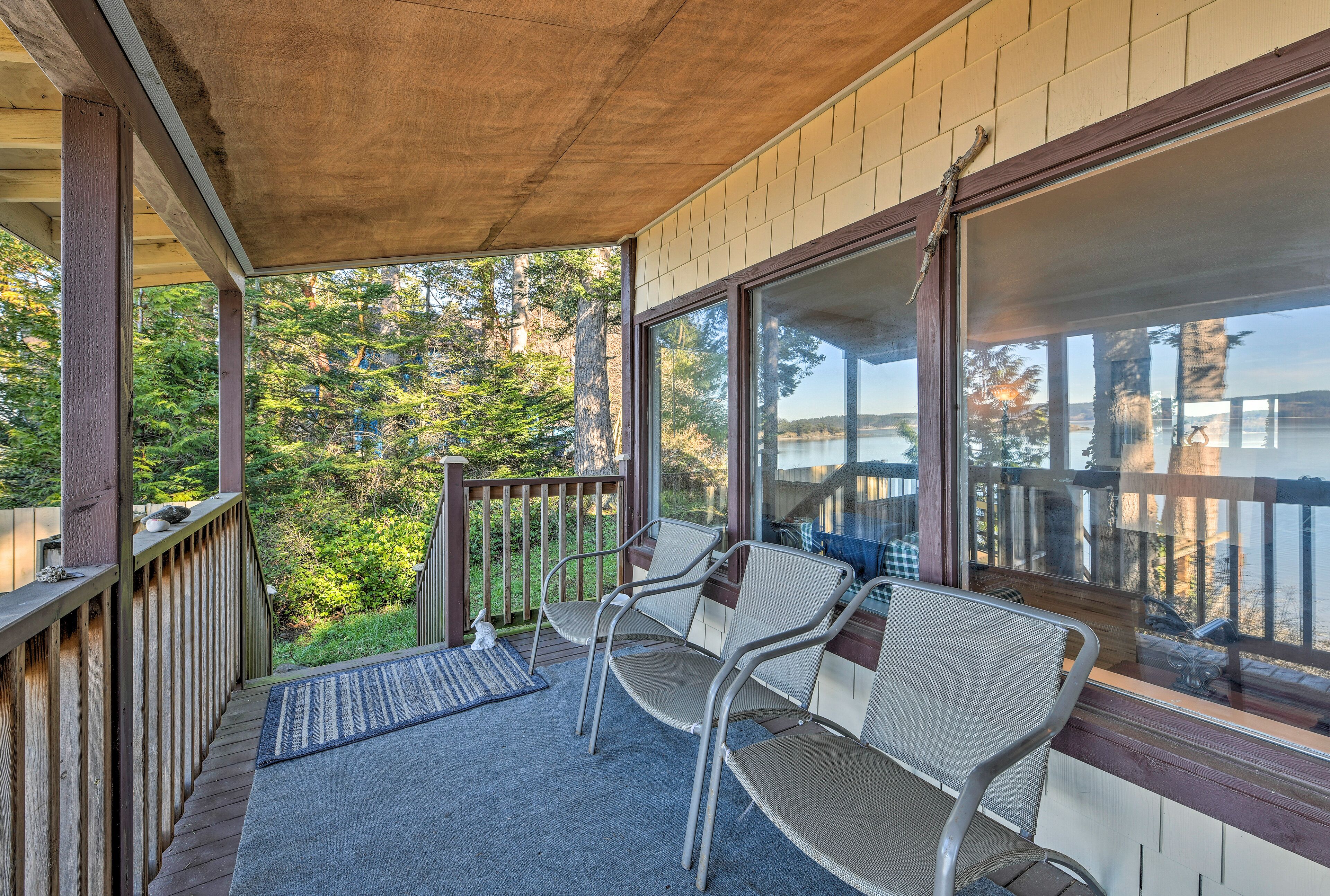 A covered porch with two metal chairs and a small rug.