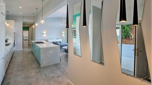 Una cucina moderna con isola centrale, illuminazione a sospensione e ampie finestre.