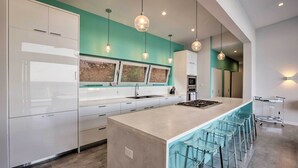 Una cucina moderna con una grande isola, sgabelli da bar e luci a sospensione.