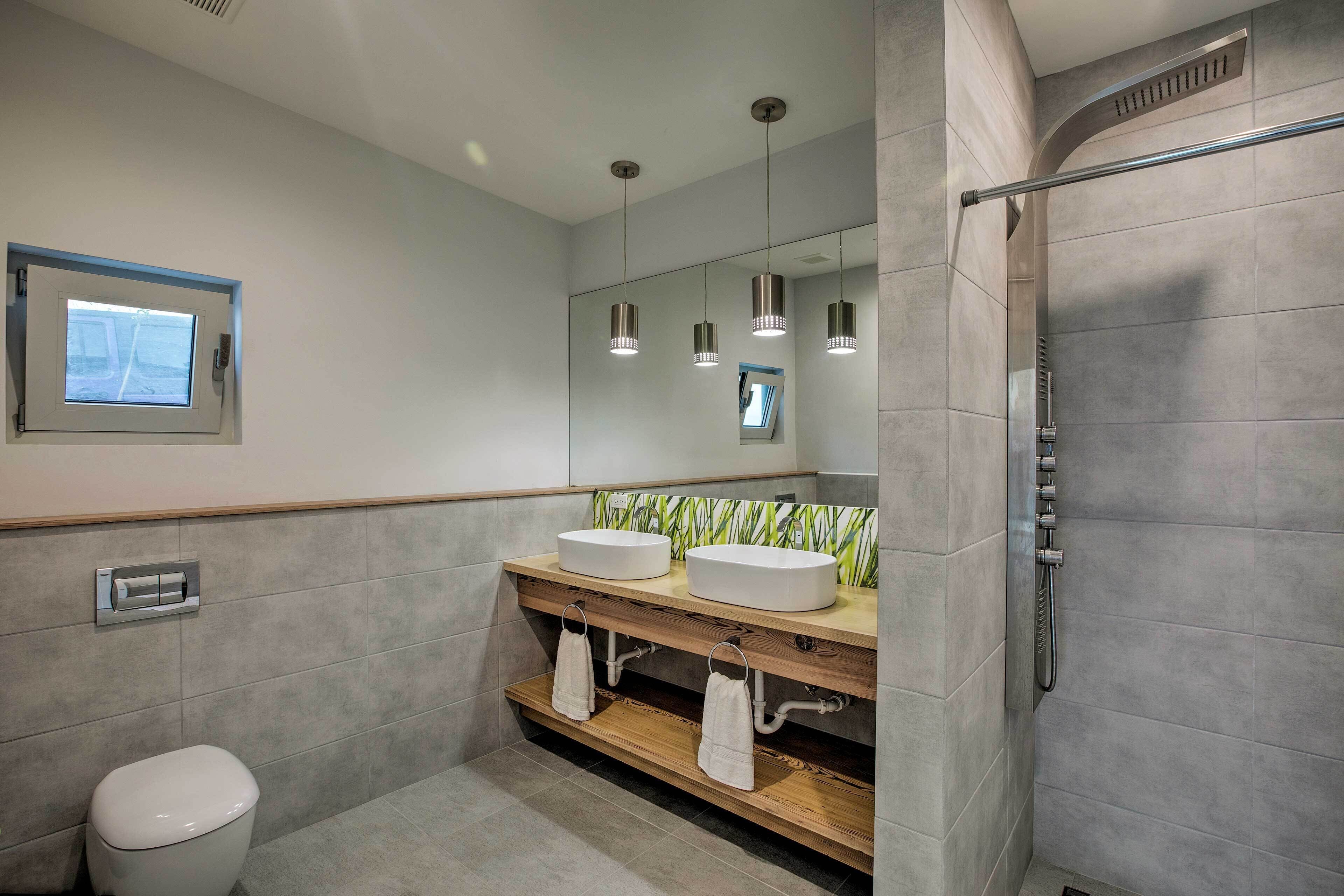 Une salle de bain moderne avec deux lavabos, des toilettes et une douche.