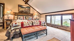 A bedroom with a large bed, a bench, a window with a view, and a painting on the wall. - 3 Mi to Beech Mtn: Treetop Cabin w/ Deck & Views (Banner Elk)