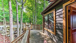 A wooden deck leading to a cabin with a stone wall and a wooden railing. - 3 Mi to Beech Mtn: Treetop Cabin w/ Deck & Views (Banner Elk)