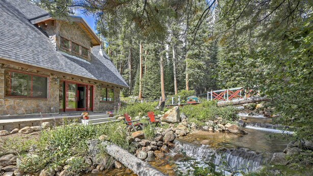 A stone building with a stone roof, a wooden deck, and a small waterfall. - Cozy Dumont Cottage With Mill Creek Views! (Dumont)
