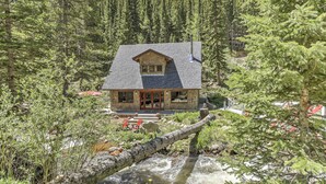 A lodge with a stone exterior, a large window, and a view of a forested area. - Cozy Dumont Cottage With Mill Creek Views! (Dumont)