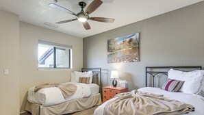 A bedroom with two beds, a ceiling fan, a nightstand with a lamp, and a window. - Sedona Condo on Golf Course w/ Mountain Views! (Sedona)