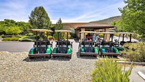 A parking area with golf carts and umbrellas, surrounded by greenery and a building in the background. - Sedona Condo on Golf Course w/ Mountain Views! (Sedona)