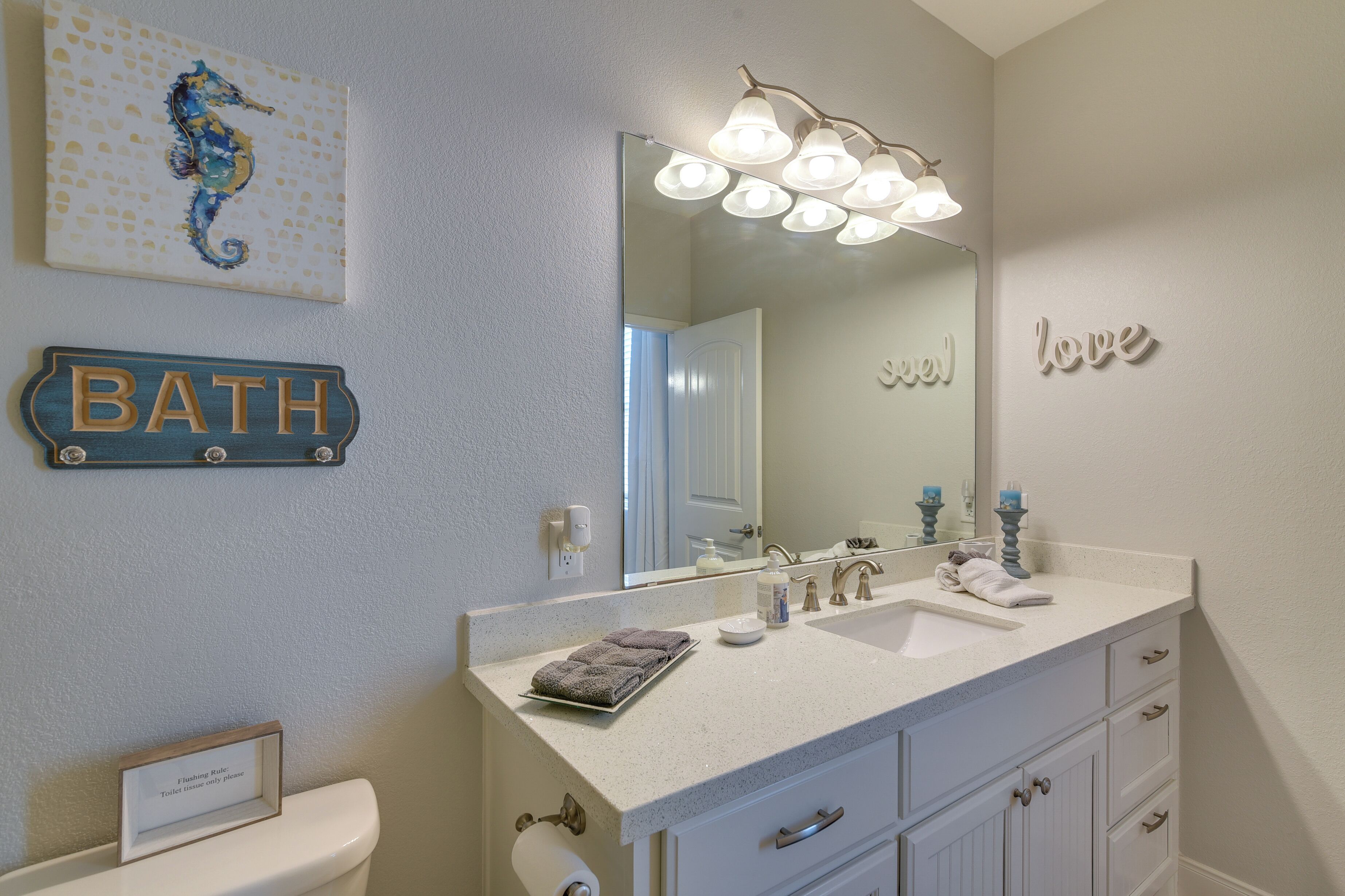 A bathroom with a sink, mirror, and a sign that reads 'BATH'.