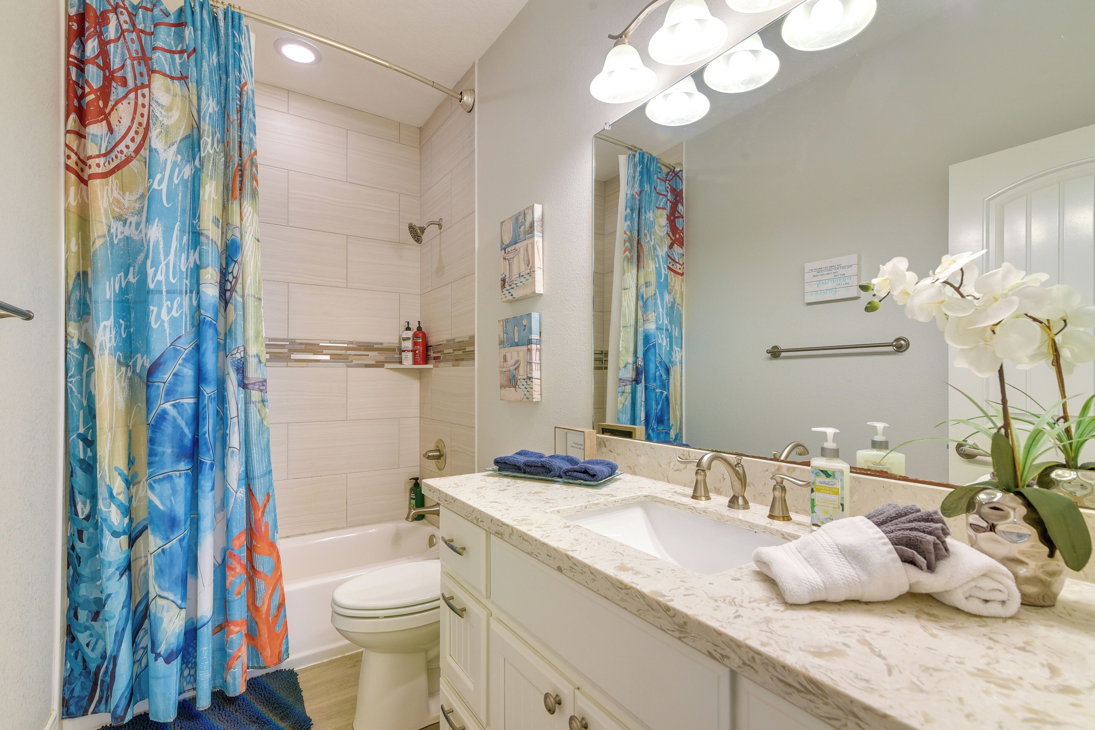 Ein Badezimmer mit Duschvorhang, Badewanne, Waschbecken mit Spiegel und Toilette.