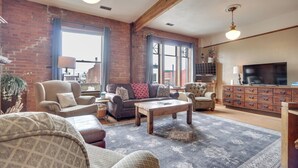 A spacious living room with a large window, a fireplace, and a television. - 1 Mi to UW: Historic Laramie Apt (Laramie)