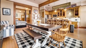 A spacious kitchen with wooden cabinets, a large dining table, and a checkered floor. - 1 Mi to UW: Historic Laramie Apt (Laramie)