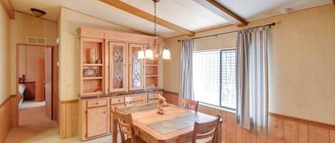 A dining area with a wooden table and chairs, a chandelier, and wooden cabinets.