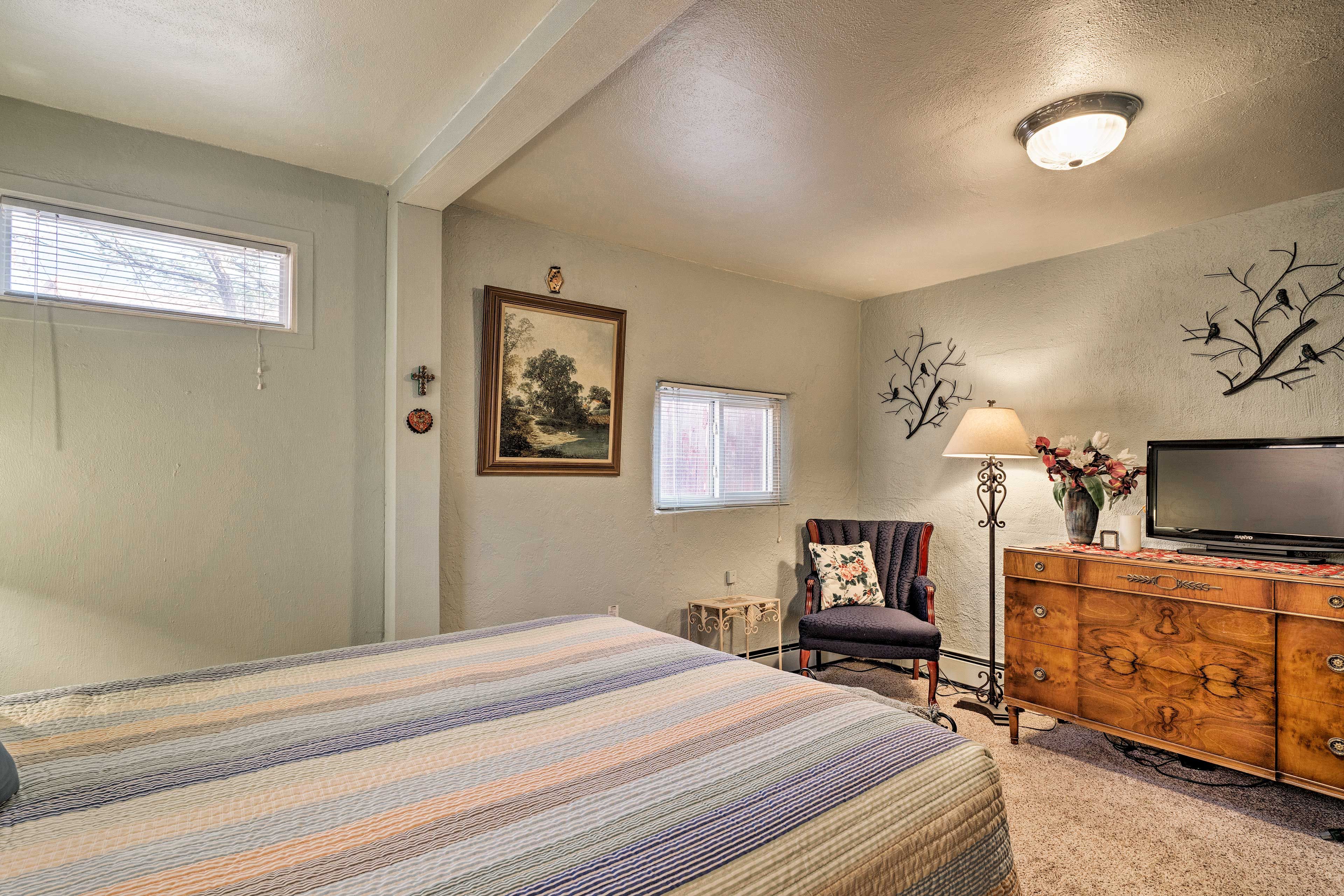 Une chambre à coucher comprenant un lit, une commode, un téléviseur et des éléments décoratifs sur les murs.