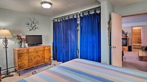 A bedroom with a bed, dresser, TV, and curtains. - Colorful Bungalow By Pikes Peak/garden of the Gods (Manitou Springs)
