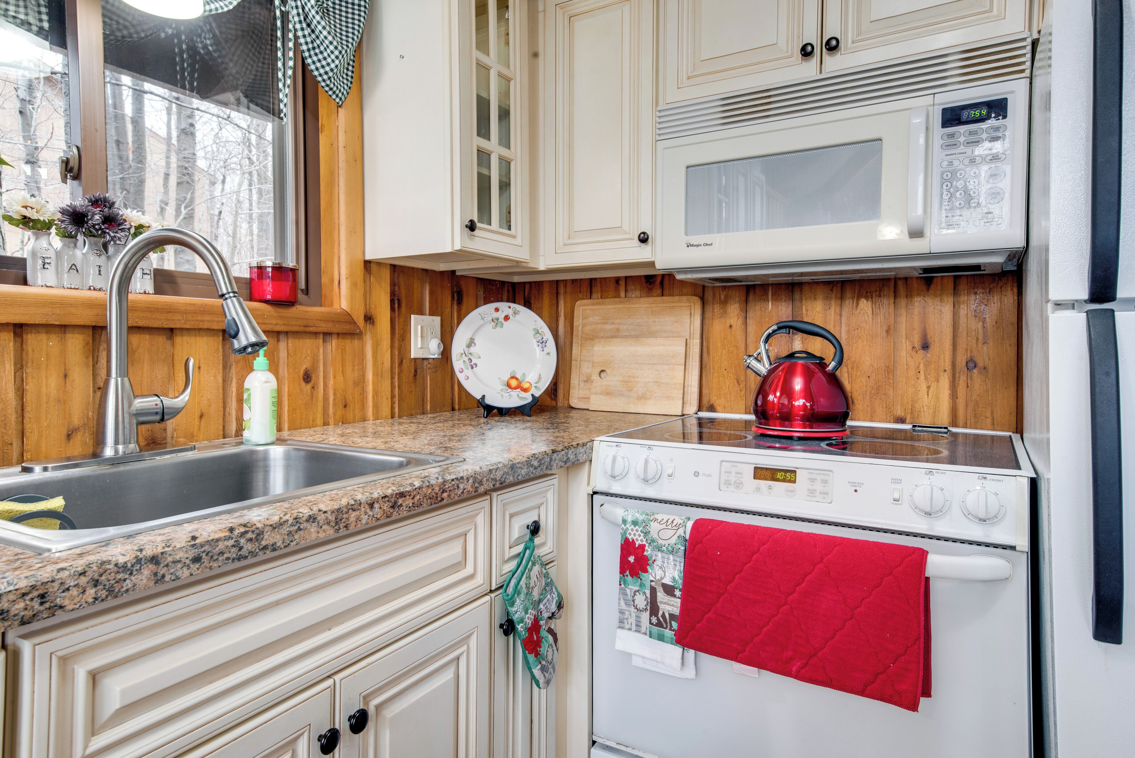 A kitchen with a sink, stove, microwave, and wooden cabinets.