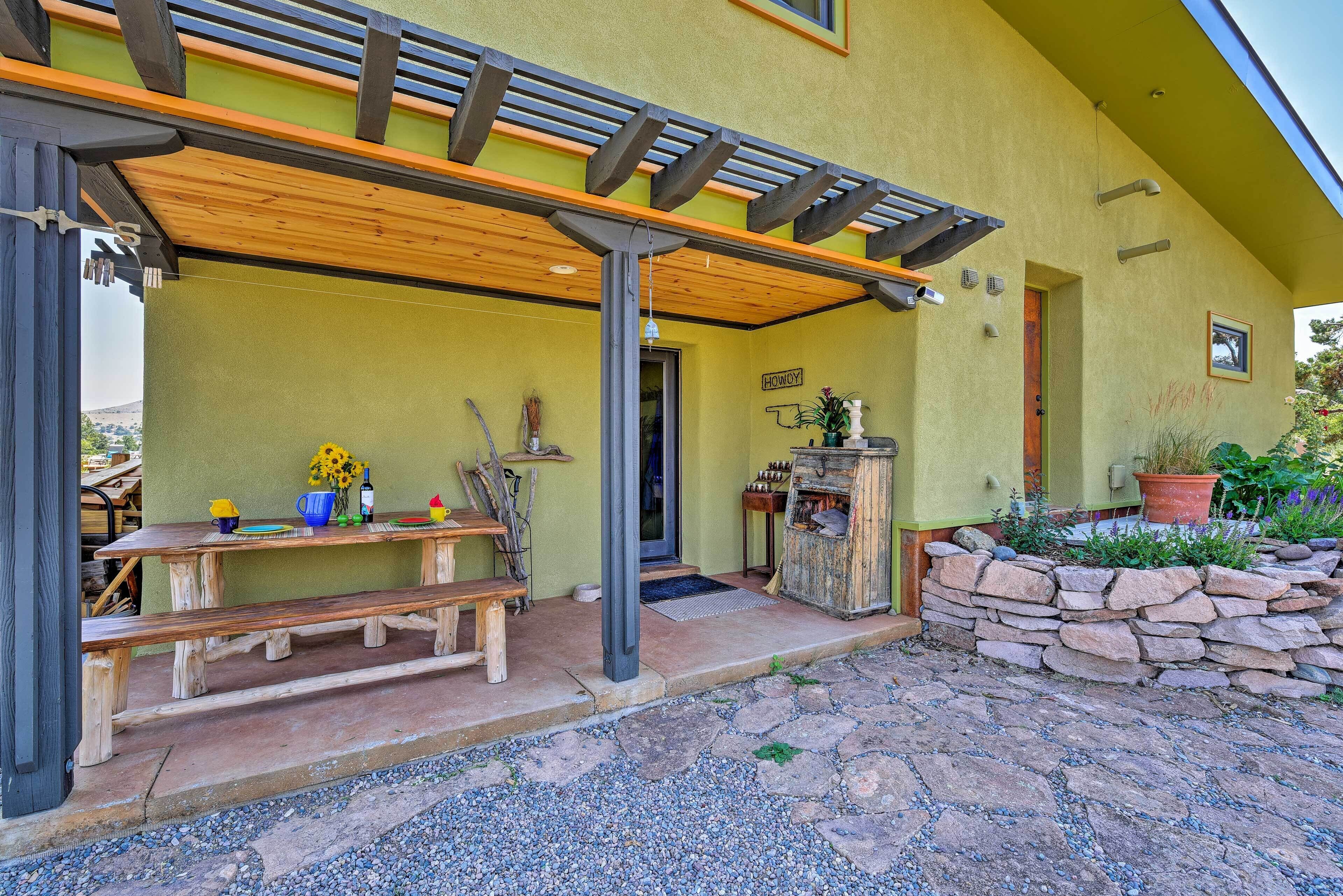 A covered patio with a wooden bench and a stone wall.