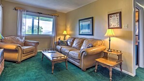 A living room with two leather sofas, a wooden coffee table, and two side tables with lamps. - Secluded Mountain Home w/ Stunning Views & Deck! (Bryson City)