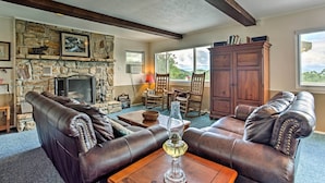 A living room with a stone fireplace, leather sofas, and a wooden cabinet. - Secluded Mountain Home w/ Stunning Views & Deck! (Bryson City)