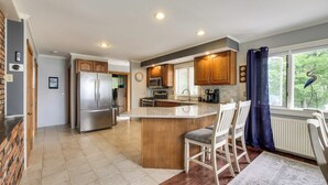 A modern kitchen with a central island, stainless steel appliances, and a view of the outdoors. - Enchanting Waterfront Sorrento Home w/ Deck! (Sorrento)