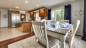 A modern kitchen with wooden cabinets, a stainless steel refrigerator, and a dining area with a wooden table and chairs. - Enchanting Waterfront Sorrento Home w/ Deck! (Sorrento)