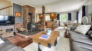 A living room with a fireplace, a television, and a sofa. - Enchanting Waterfront Sorrento Home w/ Deck! (Sorrento)
