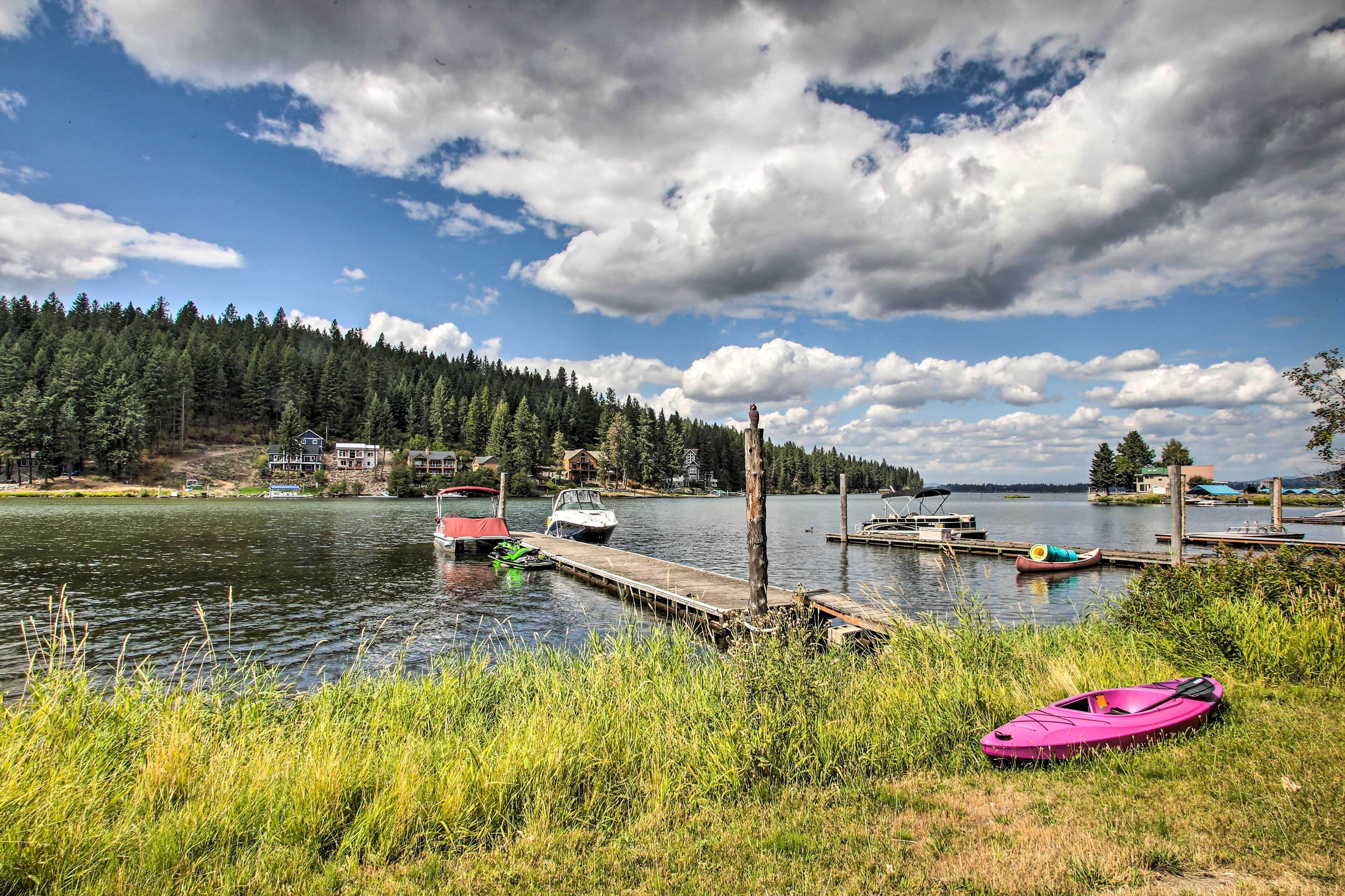 Une vue sur le lac, avec des bateaux amarrés, un kayak et une colline boisée.