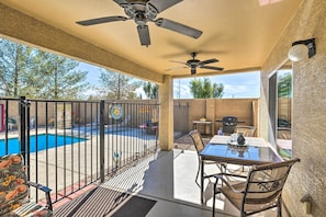 Relax by the pool in this patio area, featuring a table and chairs under a ceiling fan.