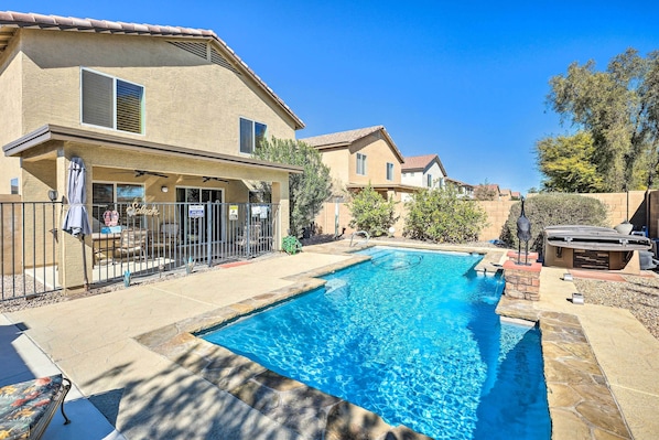 Relax by the pool surrounded by a patio area with a shaded space under a ceiling fan.