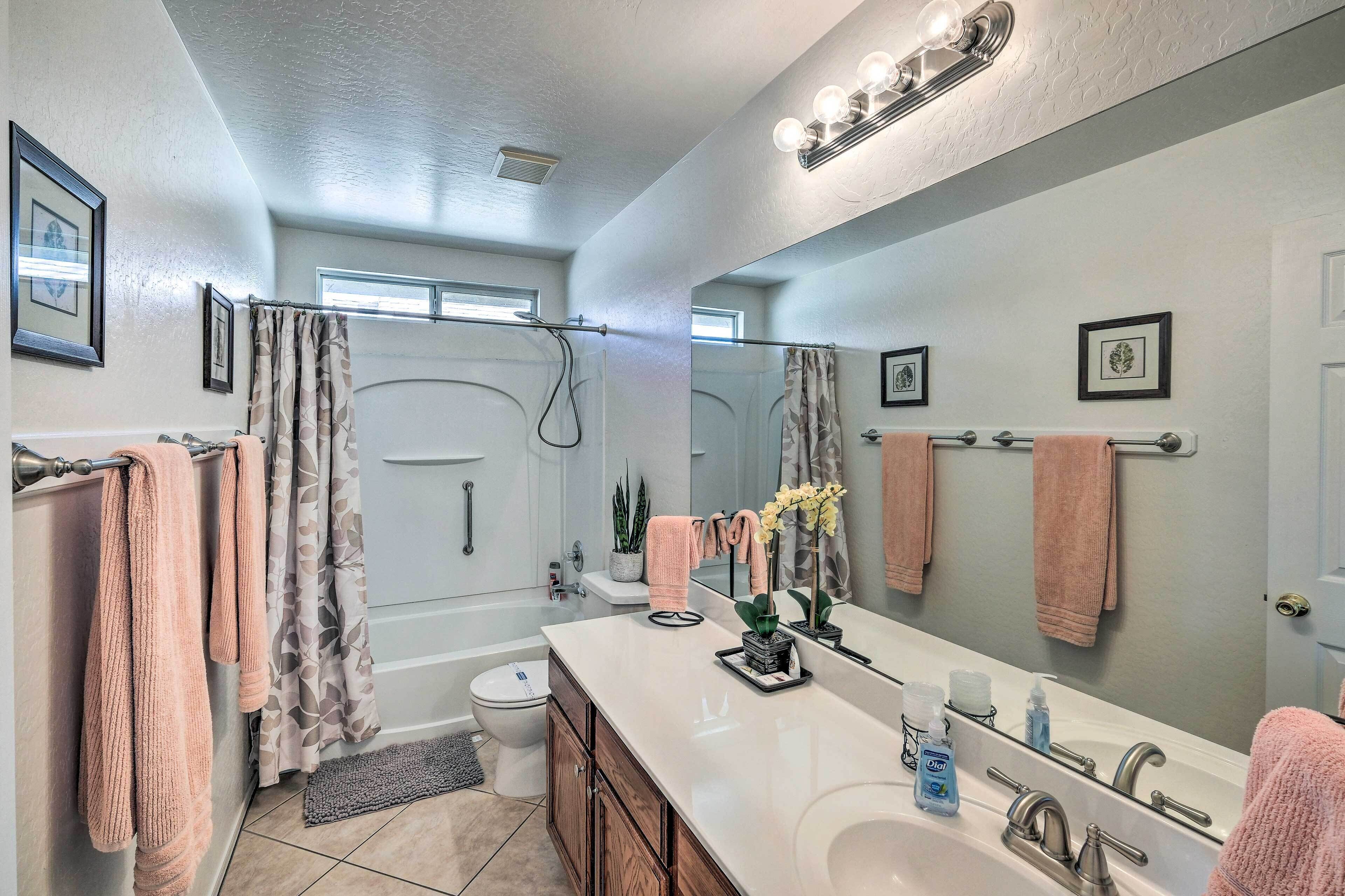 A bathroom with a large mirror, vanity, and a shower area.