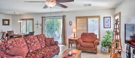 A living room with a sofa, armchair, coffee table, and a ceiling fan.