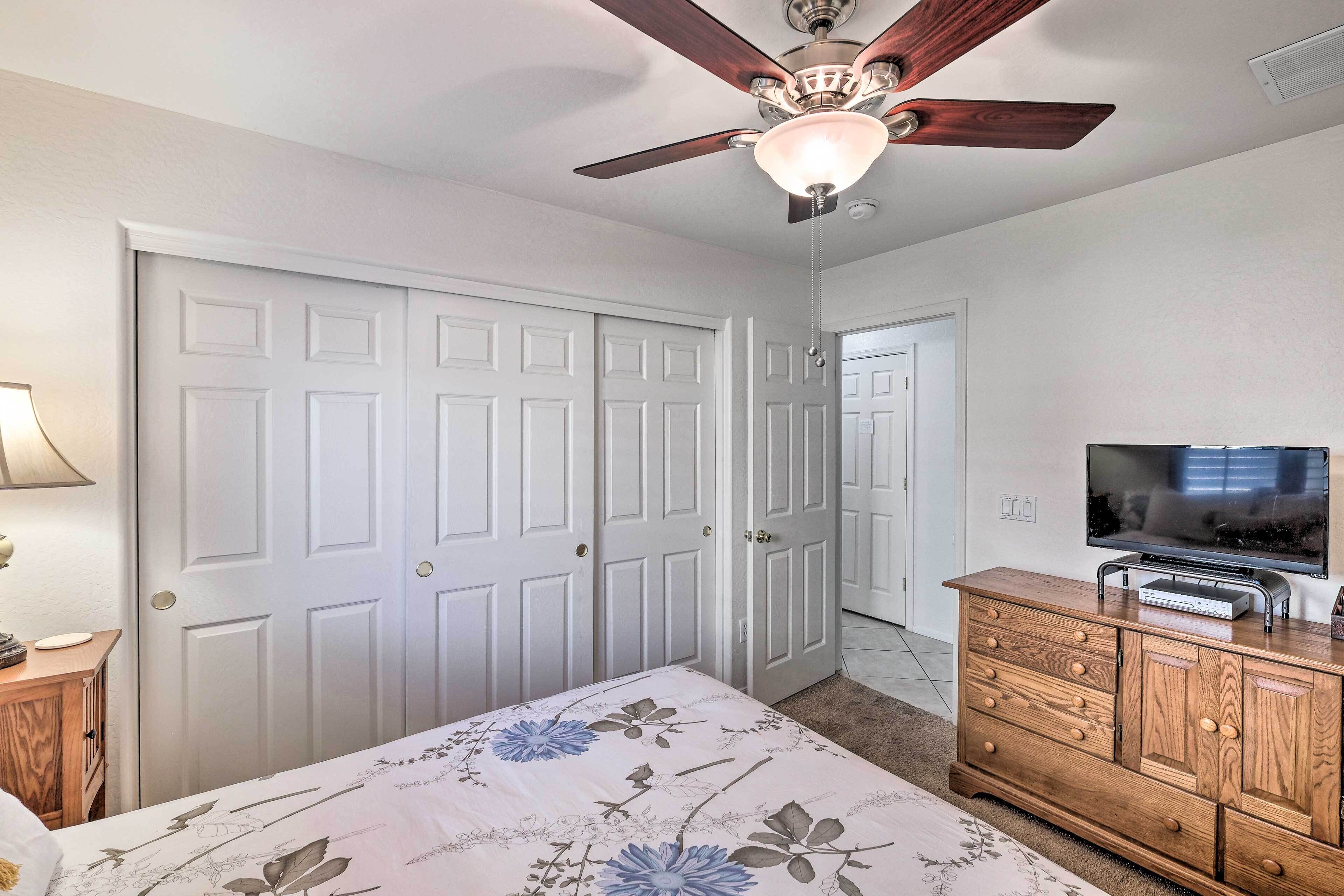 A bedroom with a bed, a dresser, a television, and a ceiling fan.